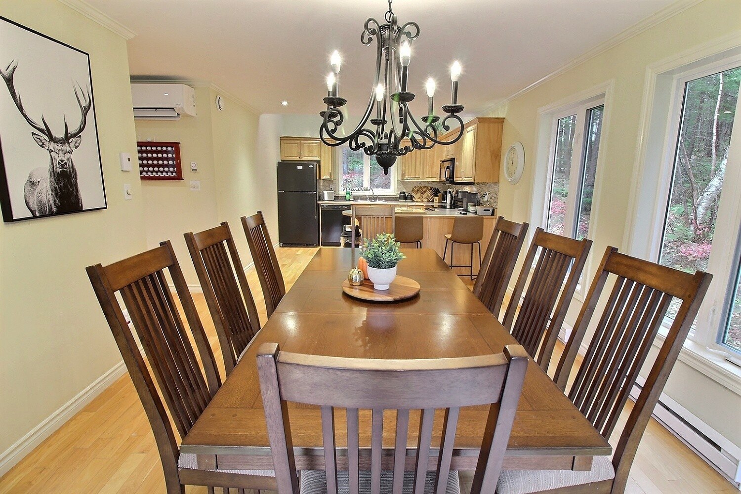 Wooden dining table with chandelier and kitchen beyond